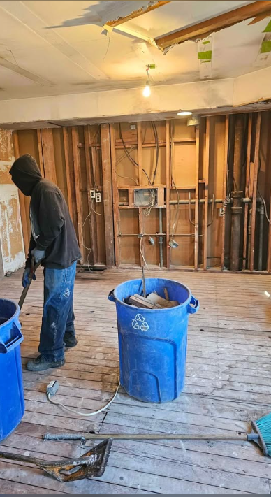 Interior stripped to studs and subfloor with debris bins on site