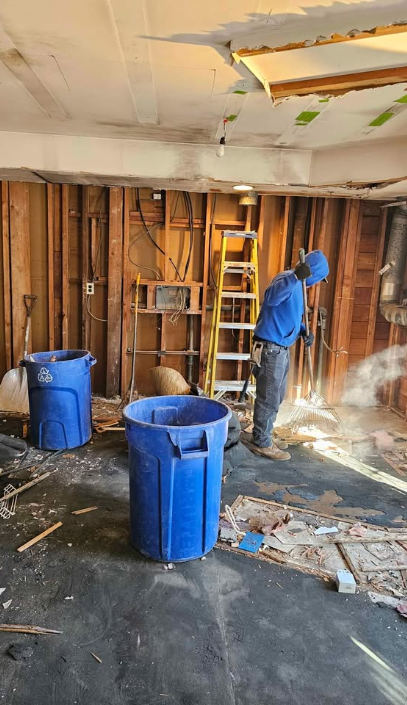 Worker sweeping debris into bins during a basement demolition