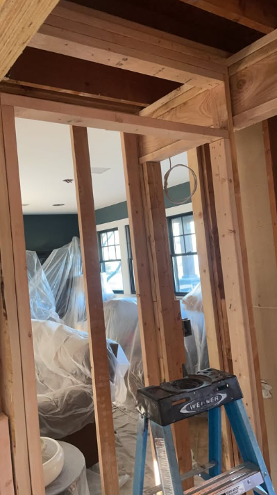 Wall opened to framing with furniture protected in plastic sheeting